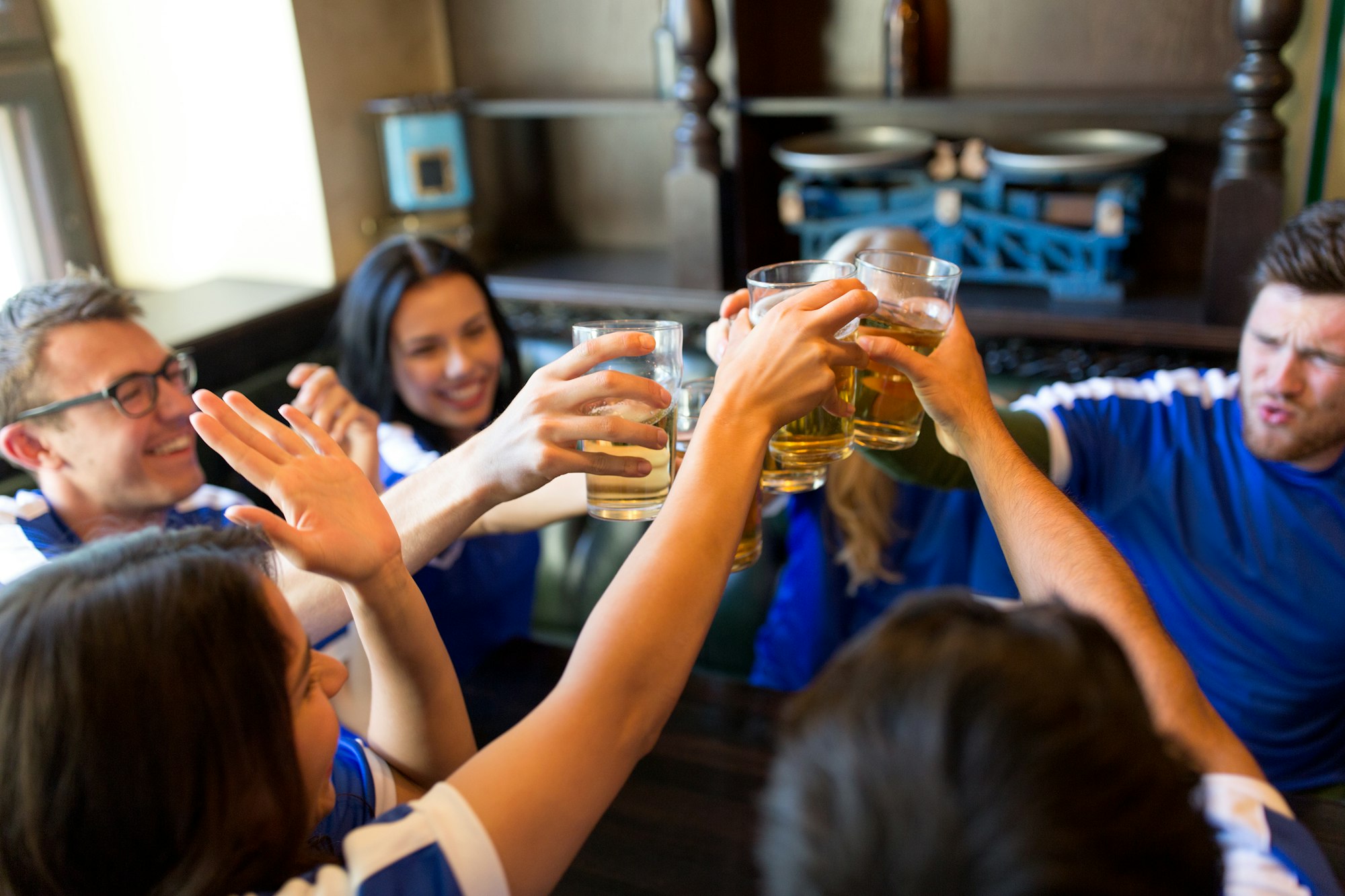 football fans clinking beer glasses at sport bar